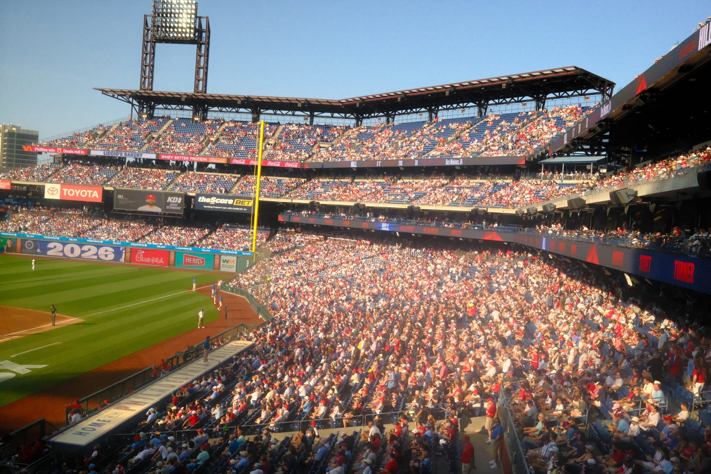 A full Citizens Bank Park in evening sun, the crowd lit gold along the third-base line